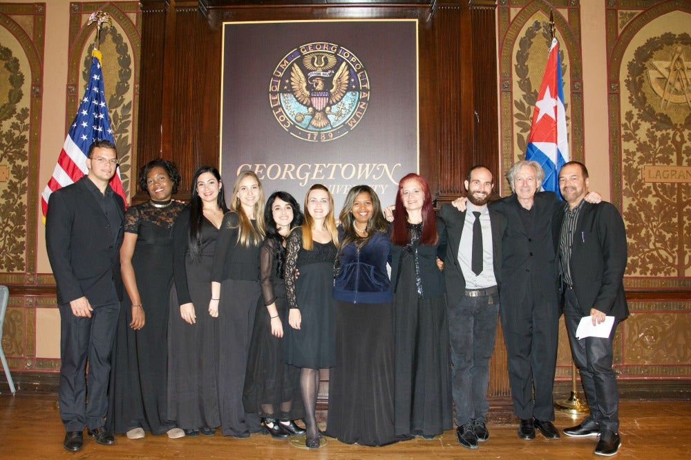 Group of students with professor in front of GU sign, American and Cuban flags