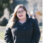 Amanda, standing on Copley Lawn, wearing black glasses, red lipstick, and a grey coat