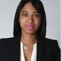 A headshot of Kala, wearing a white blouse and black blazer, 