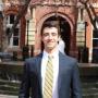 Michael, wearing a suit with a yellow and blue striped tie, standing in Dalhgren Quad