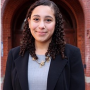 Sofia, wearing a grey blouse and black blazer, standing in front of Dahlgren Chapel 