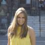 Stacie, wearing a yellow tank top, smiling, in front of the steps of Healy Hall