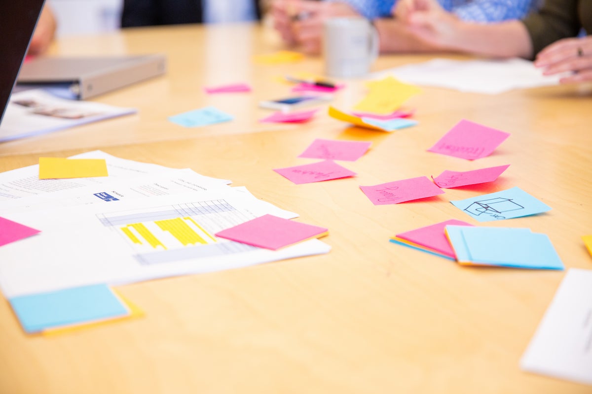 A table with papers and different colored sticky notes.