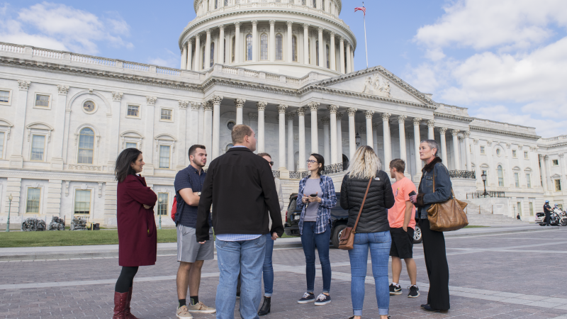 A group of people stand outside the US Capitol building.