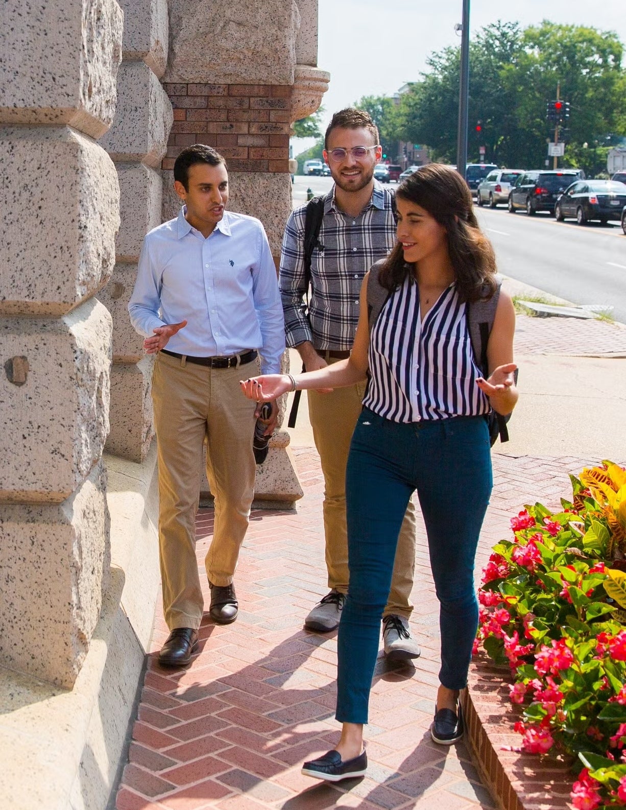 Three graduate students walking together outside.