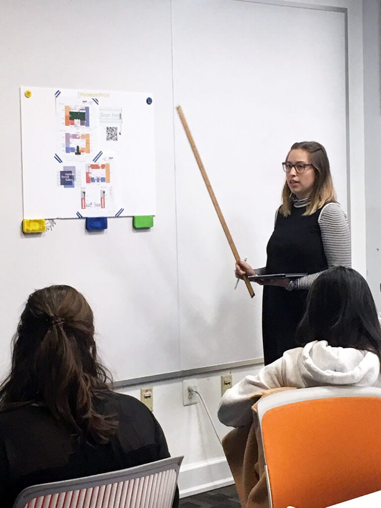 person standing in front of a whiteboard with a ruler - post-its on the whiteboard