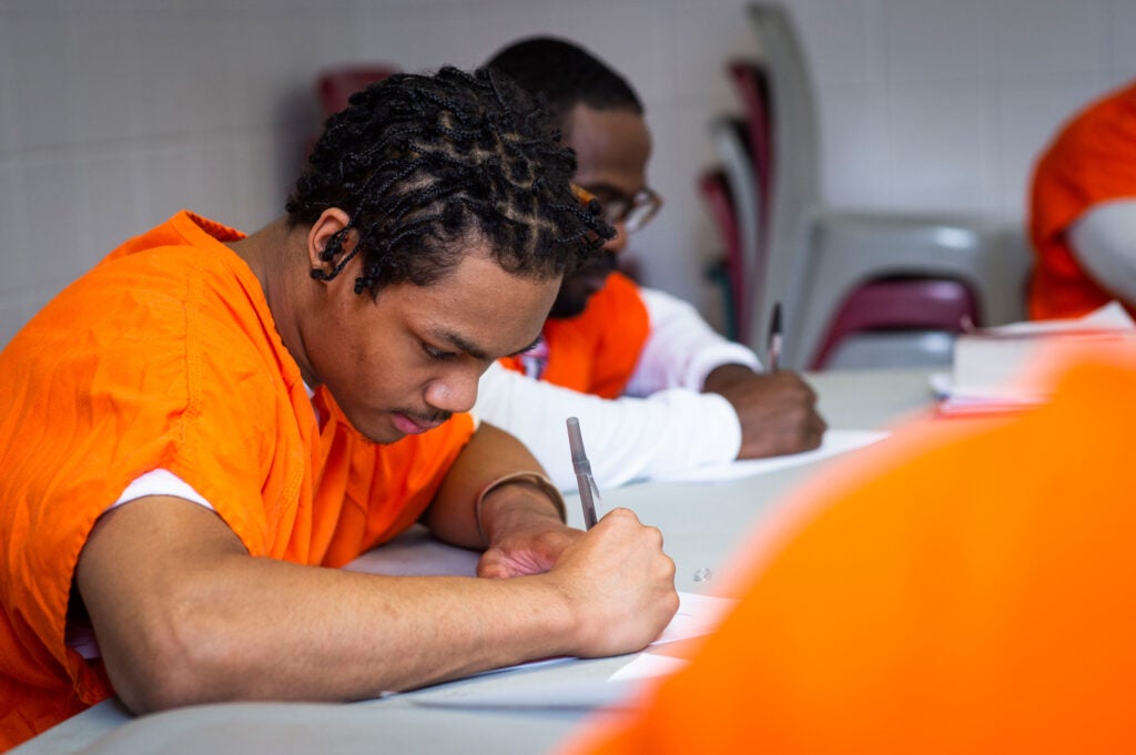 An incarcerated man writing in a classroom.