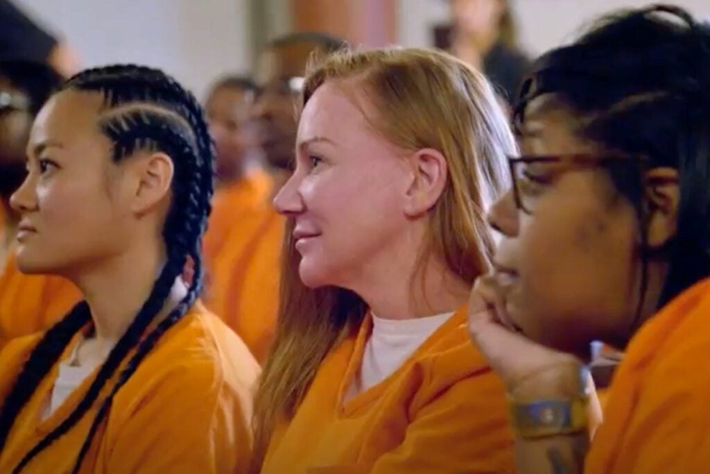 Three incarcerated women seated next to each other during an event.