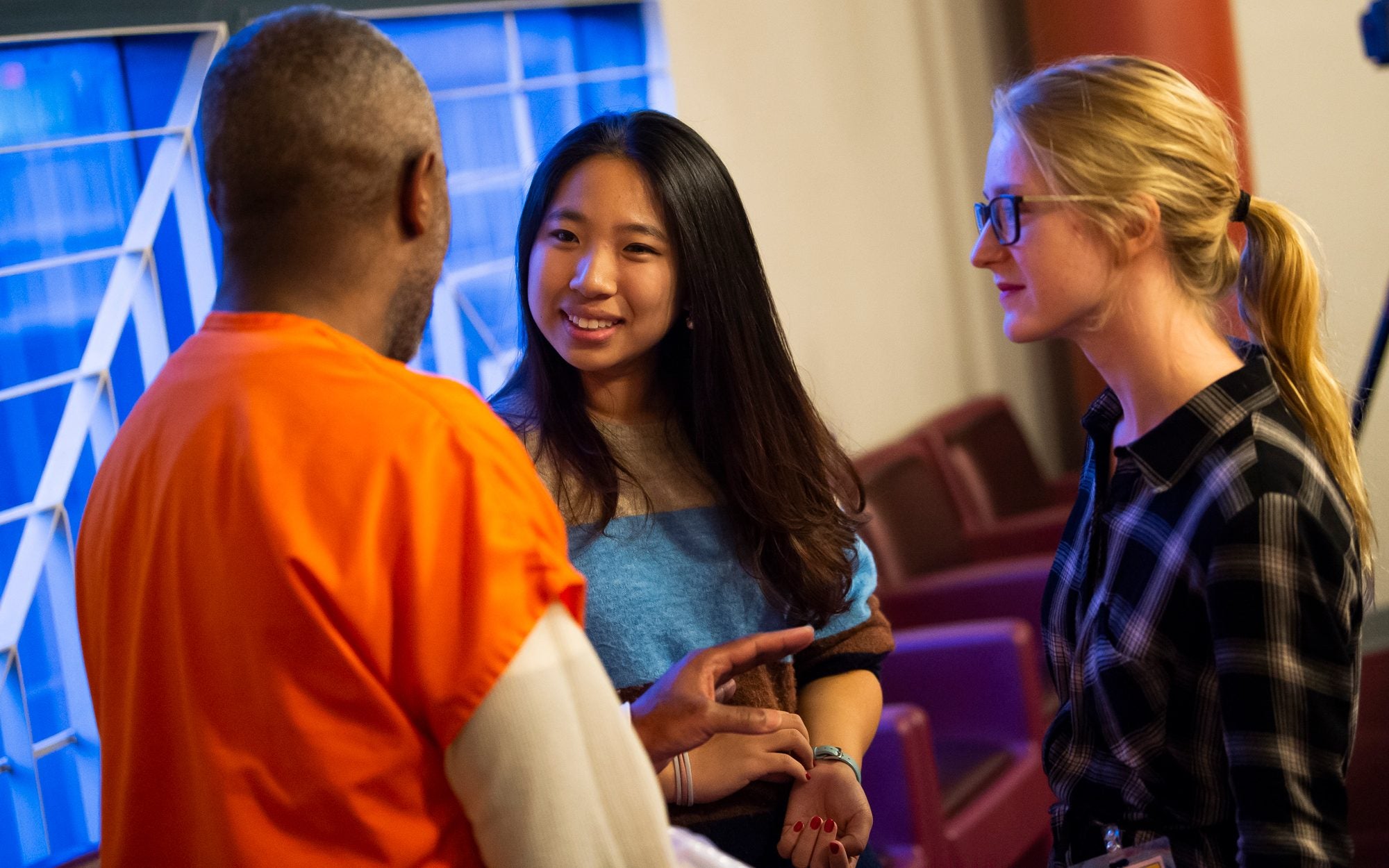Two young women speak with an incarcerated man.
