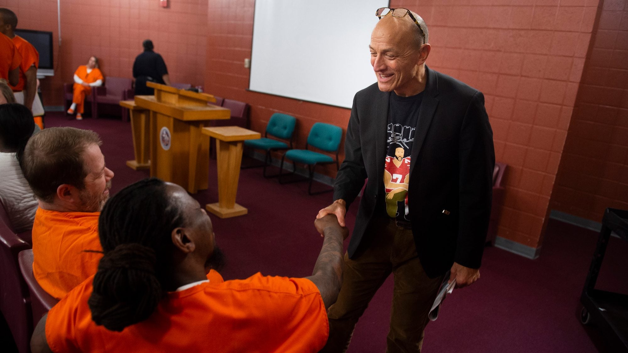 A professor shakes hands with an incarcerated student.