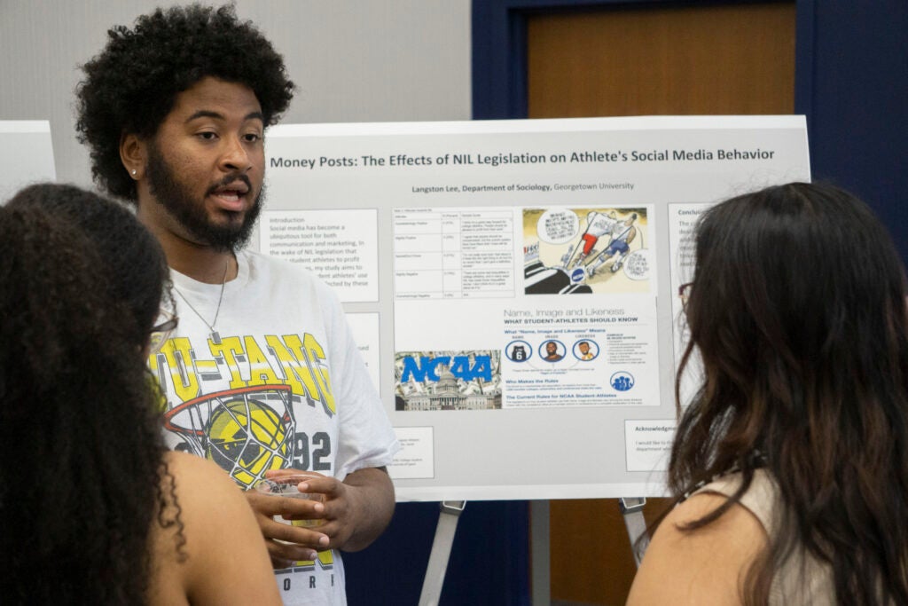 Senior Langston Lee discusses their presentation with two community members