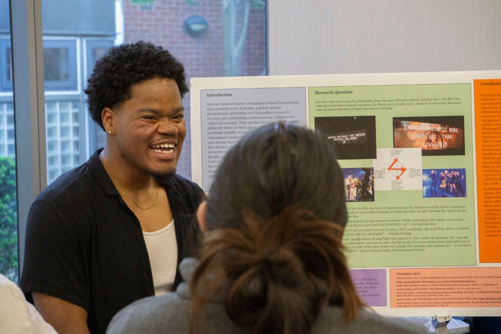 Senior Nicolas Stewart laughs while discussing their presentation with community members