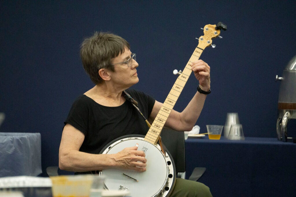 Professor Sarah Stiles performs a song on the banjo while seated