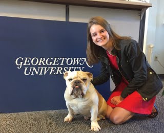 CC Borzilleri with Jack the bulldog in front of desk that has "Georgetown University" text