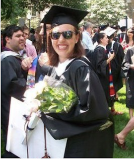 Lucy Obus wearing her cap and gown with a bouquet of flowers