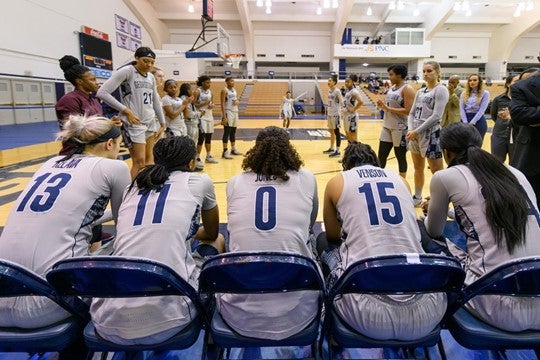 Georgetown Women's basketball team sitting at the edge of the court